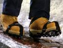 Navigating over melting snow/ice is a person in work-boots with the product strapped on to each boot.