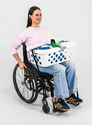 Woman in a wheelchair with a laudry basket on her lap and a LapStacker belt securing the basket so that she can use both hands freely.