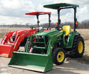 An orange and a green tractor each with a canopy attached to the ROPS