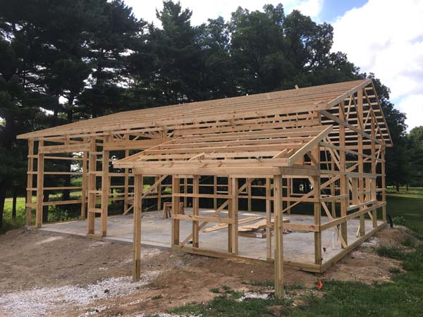 Pictured in a workshop in the process of being built, its concrete floor already laid and the wood studs and roof lengths in place, ready to be covered.