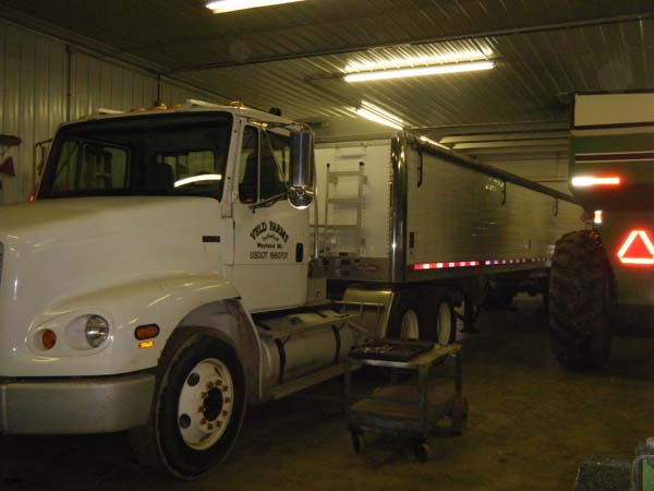 Pictured is a portion of a top-florescent-lighted workshop’s equipment maintenance area that’s adequately accommodating a large grain truck and a tractor.