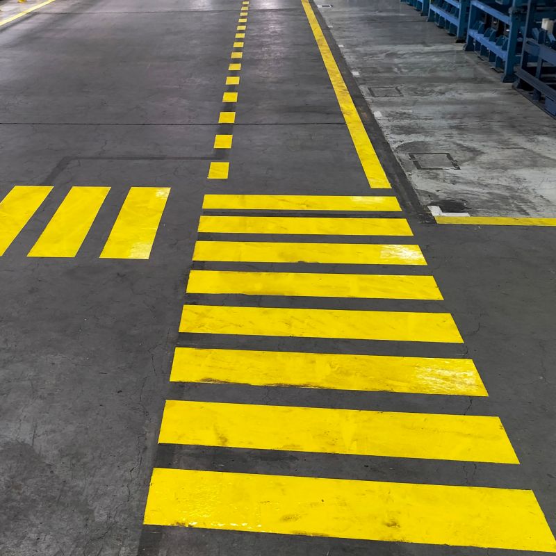 Various fluorescent yellow markings on a shop floor to indicate paths of travel