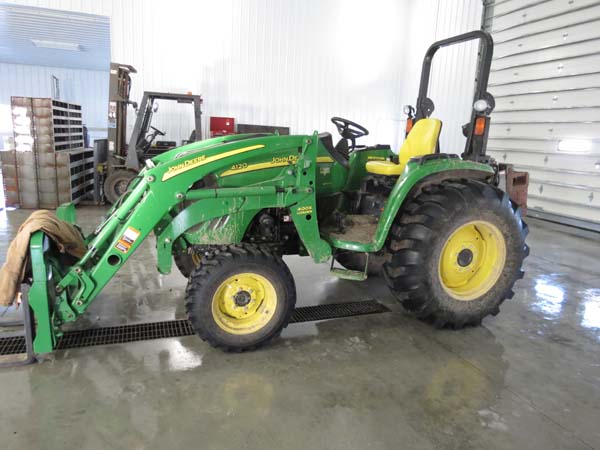 Utility tractor parked inside shop on sloped concrete floor