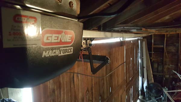 Pictured is a powered garage-door opener custom-bracketed to a farm building’s wooden door.