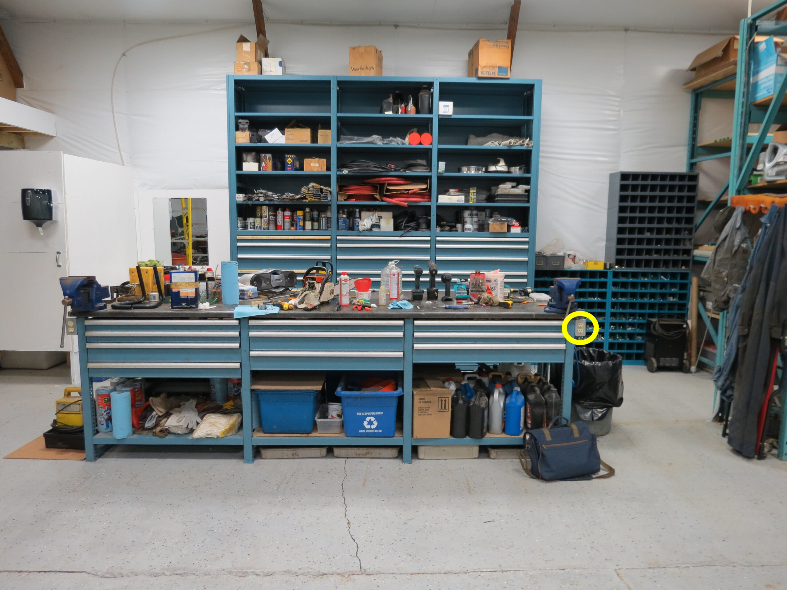 Pictured affixed at the left and right corners of a 10-foor-long workbench with numerous items on top and beneath are electrical outlets accessible to the shop’s power-tool cords.