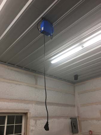 Pictured is the ceiling-attached, 4-foot-long LED light housing; a few feet away (also ceiling attached, is a box from which a rewind electric cord is hanging,