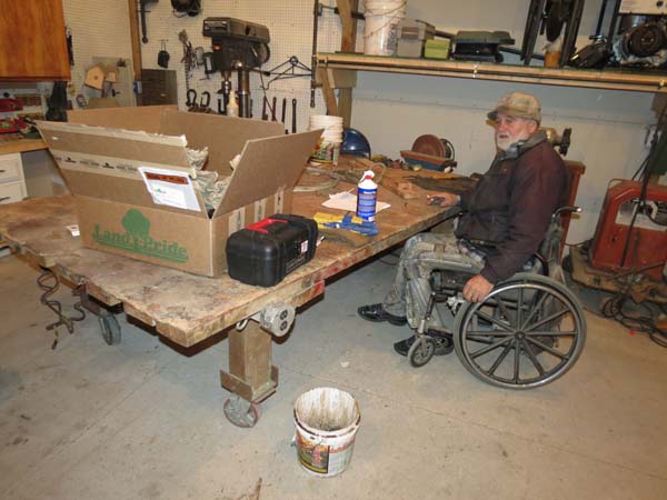 Pictured is a workbench raised high enough (via its 6 x 6 wood ‘legs’) that the lower portion of the adult male’s wheelchair fits under the bench, allowing him to more fully access the bench.