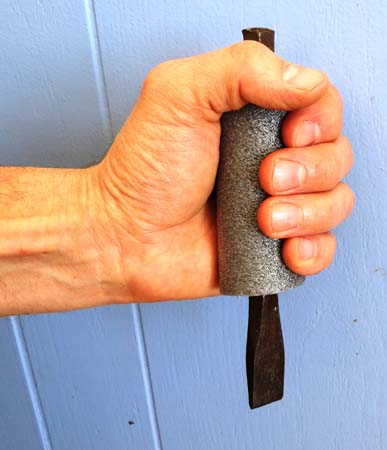 Pictured is an adult male’s hand grasping a cushioned grip of pipe insulation that’s been inserted over a metal chisel