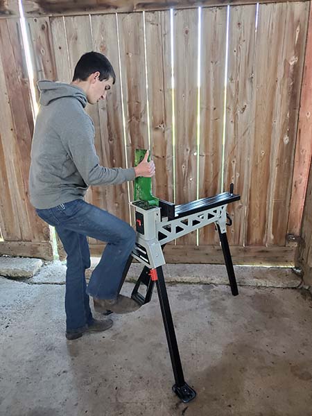 Man using foot to lock clamp on sawhorse